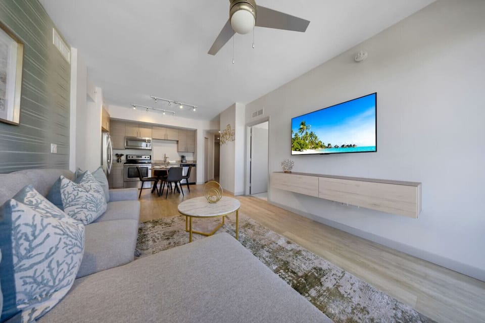 Modern Living & Dining Area-Comfortable lounge with a sectional sofa, flat-screen TV, and open layout leading to a fully equipped kitchen and dining space—perfect for relaxing or entertaining.