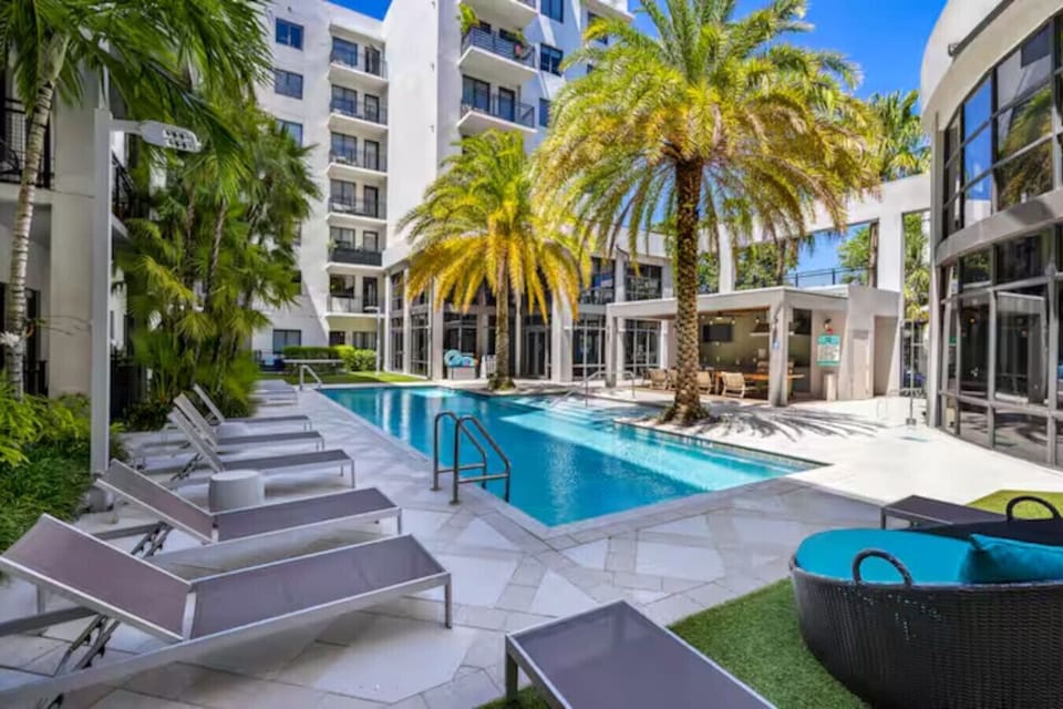 Resort-Style Pool Retreat-Relax in a stunning outdoor pool surrounded by palm trees, modern loungers, and a stylish cabana lounge area—perfect for sunbathing, swimming, or unwinding in a tropical atmosphere.