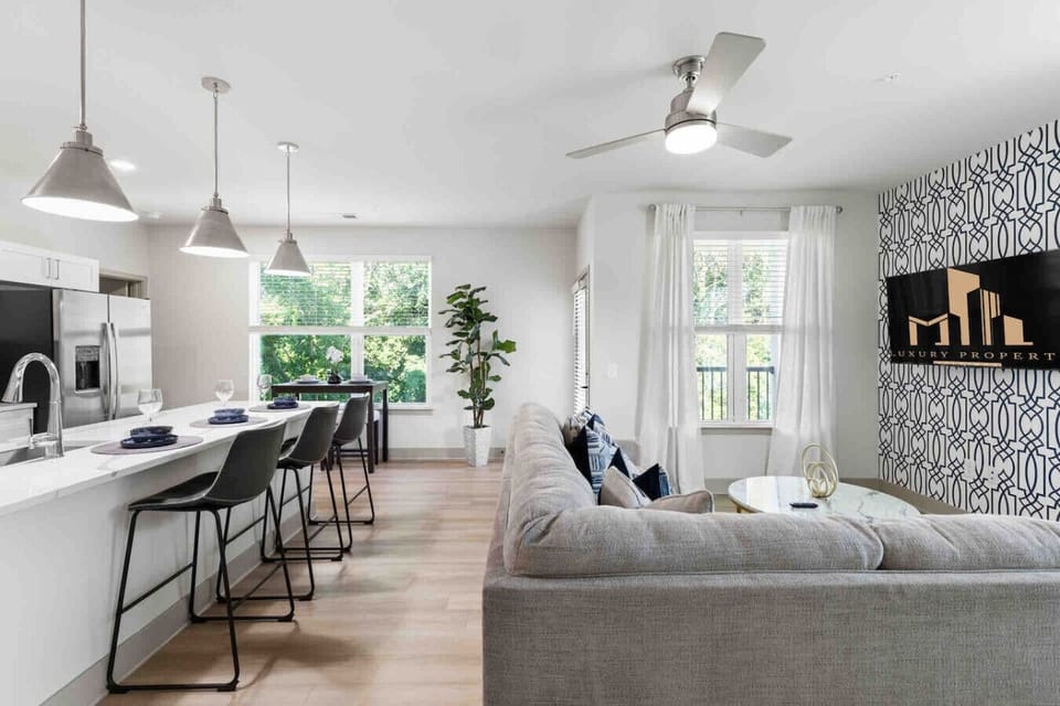 Stylish Open-Concept Living-Contemporary space featuring a sleek kitchen with bar seating, cozy sectional sofa, and large windows bringing in natural light for a bright, welcoming atmosphere.