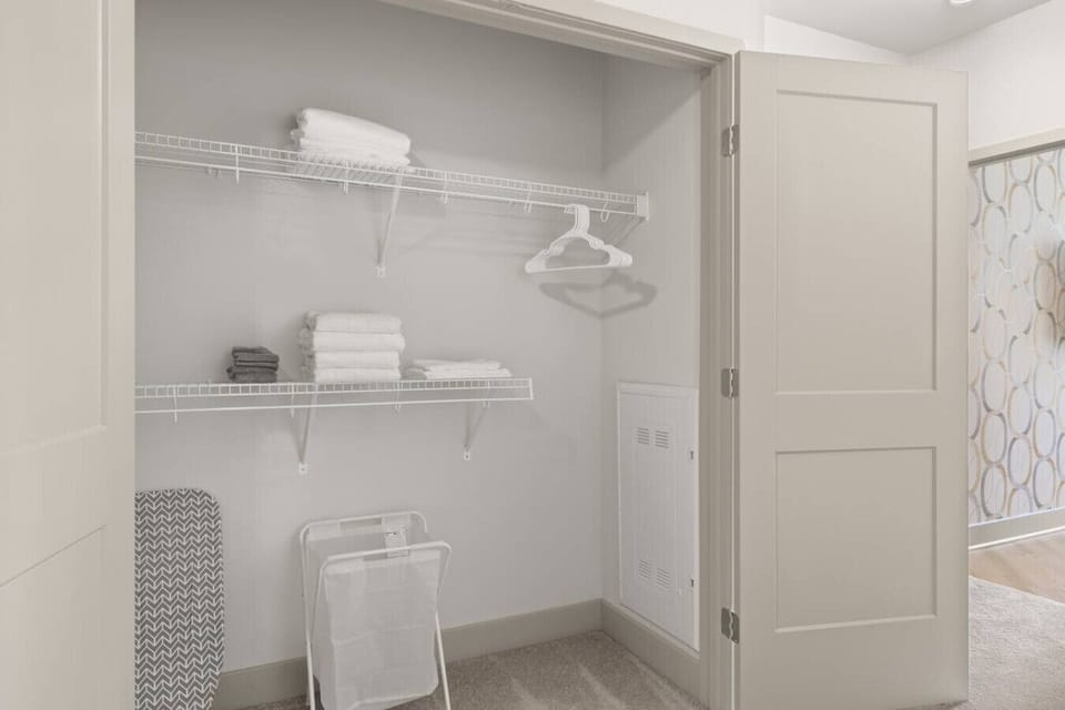 Organized Closet Space-Spacious closet with wire shelving, fresh linens, hangers, and storage essentials. Includes an ironing board and laundry basket for added guest convenience during their stay.