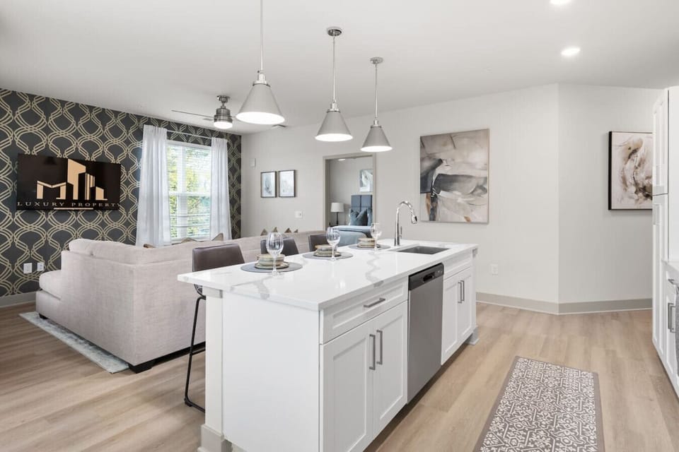 Stylish Kitchen & Living Space-Bright open-concept design with a modern island, bar seating, stainless steel appliances, and chic accent wall. Perfect for cooking, entertaining, and relaxing in a warm, inviting atmosphere.