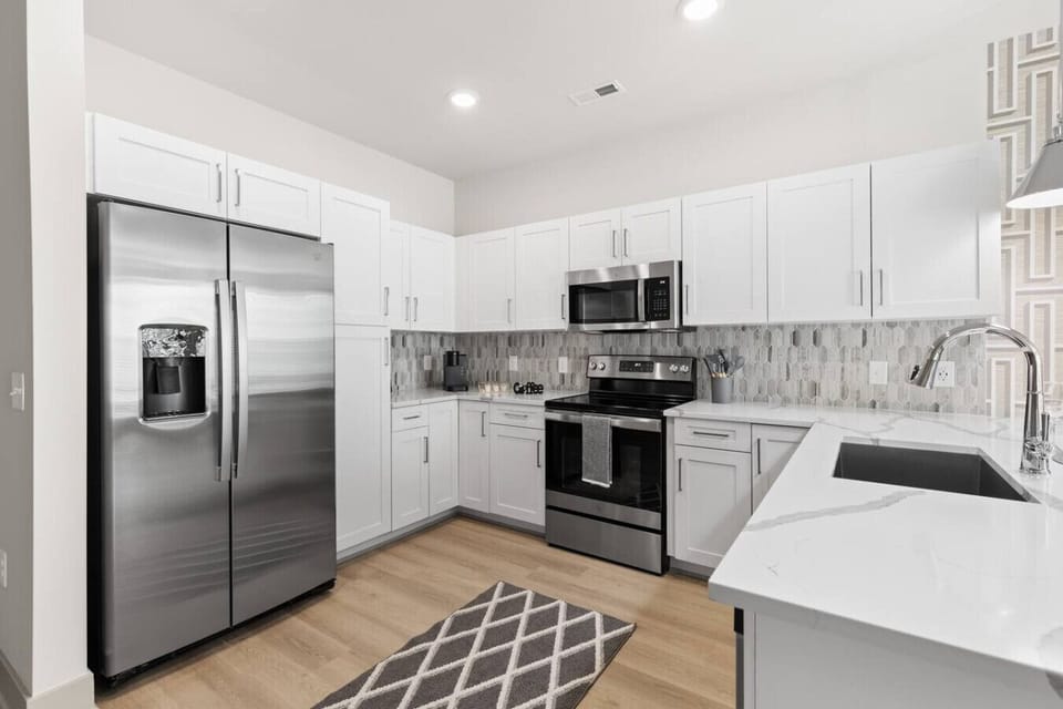 Modern Chef’s Kitchen – Sleek space with stainless steel appliances, white cabinetry, and quartz countertops. Stylish backsplash and open layout make cooking and entertaining both easy and enjoyable.