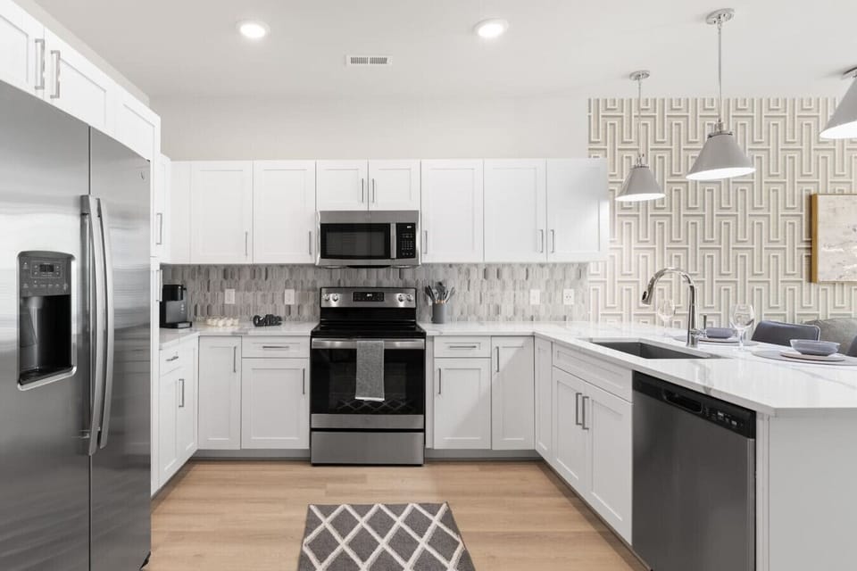 Bright Open Kitchen – Contemporary design with stainless steel appliances, white cabinetry, and quartz counters. Pendant lighting highlights the island, seamlessly connecting to the living area for easy entertaining.