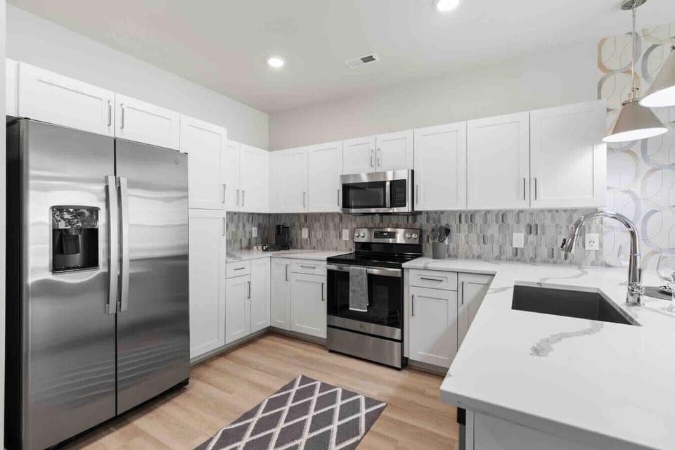 Sleek Modern Kitchen-Contemporary kitchen with stainless steel appliances, ample white cabinetry, and elegant backsplash. Designed with style and function for a comfortable cooking experience.