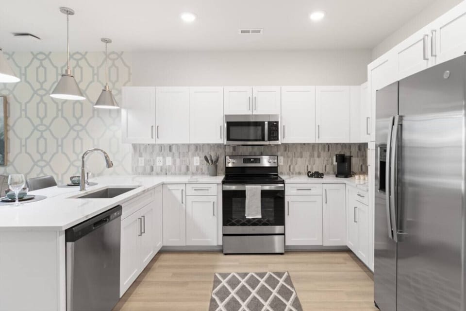 Modern Chef’s Kitchen-Spacious kitchen with stainless steel appliances, sleek white cabinetry, and stylish lighting. Features a large countertop, dishwasher, and open layout ideal for cooking and entertaining.