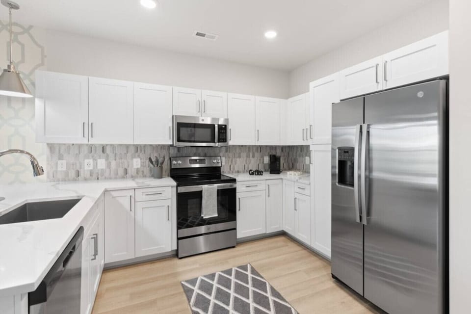Modern Chef’s Kitchen-Spacious kitchen with stainless steel appliances, sleek white cabinetry, and stylish lighting. Features a large countertop, dishwasher, and open layout ideal for cooking and entertaining.