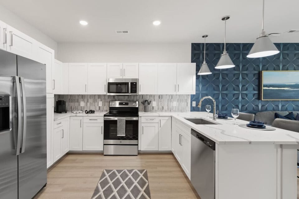 Sleek Modern Kitchen-Contemporary kitchen with stainless steel appliances, ample white cabinetry, and elegant backsplash. Designed with style and function for a comfortable cooking experience.