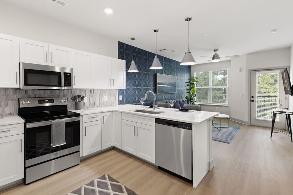 Open-Concept Kitchen-Modern kitchen with stainless steel appliances, white cabinetry, and stylish backsplash. Overlooks the living area with natural light, creating a bright and inviting open layout.