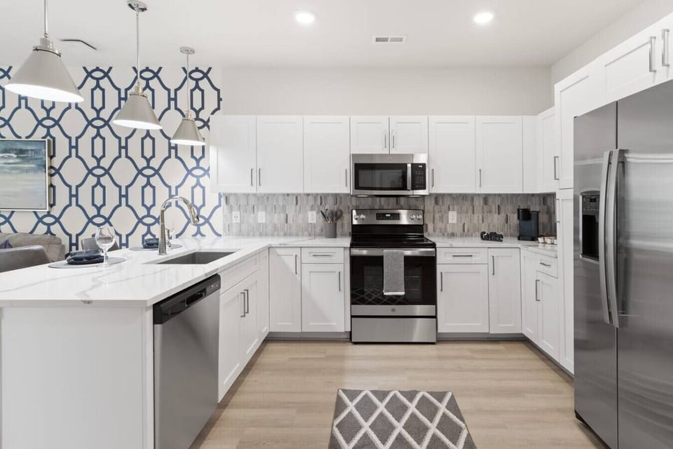Sleek Modern Kitchen-Fully equipped kitchen with stainless steel appliances, white cabinetry, and a stylish backsplash. Features a spacious layout, island seating, and bright lighting for cooking and entertaining.