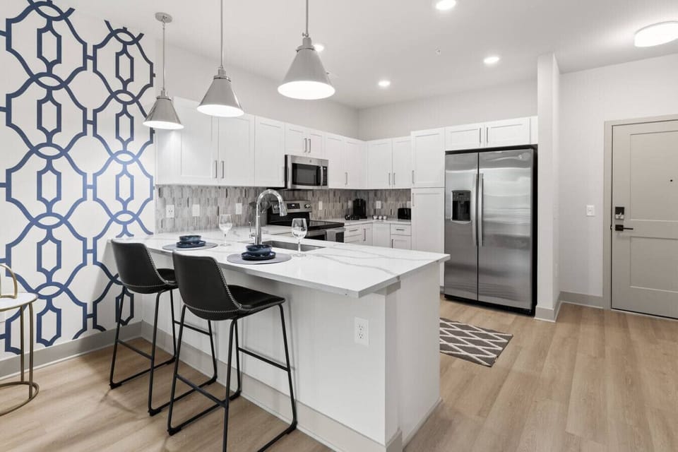 Sleek Modern Kitchen-Fully equipped kitchen with stainless steel appliances, white cabinetry, and a stylish backsplash. Features a spacious layout, island seating, and bright lighting for cooking and entertaining.