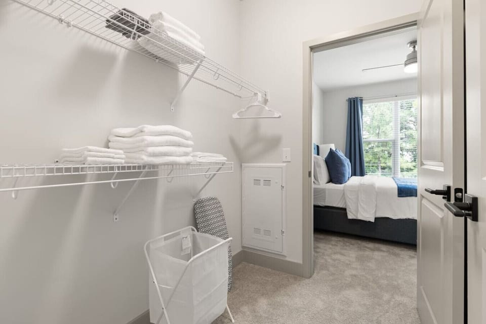 Organized Walk-In Closet-Spacious walk-in closet with wire shelving, fresh linens, and storage essentials. Includes hangers, laundry basket, and ironing board for a convenient and tidy stay.