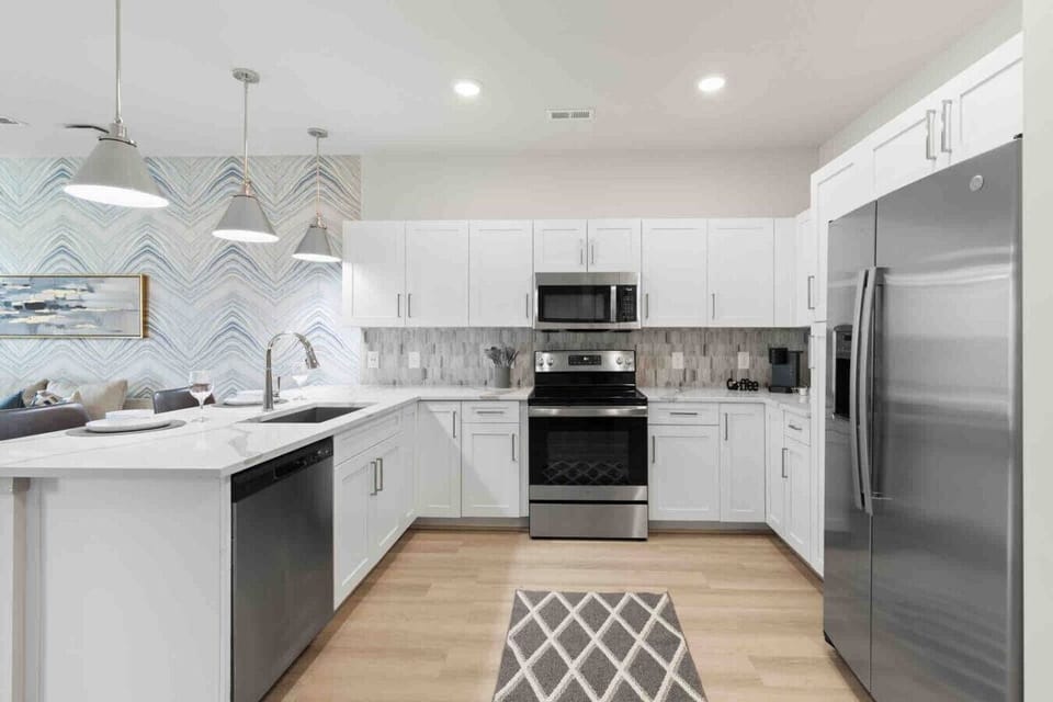 Modern Chef’s Kitchen – Sleek space with stainless steel appliances, white cabinetry, and quartz countertops. Stylish backsplash and open layout make cooking and entertaining both easy and enjoyable.