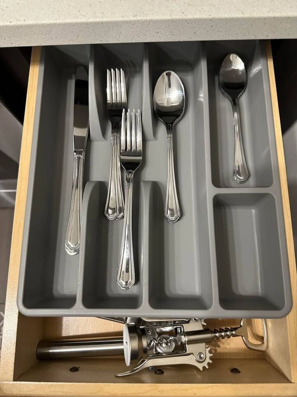 Organized Kitchen Essentials – Drawer neatly stocked with forks, spoons, knives, and additional tools including a corkscrew and can opener, providing guests with everything needed for convenient dining and meal preparation.