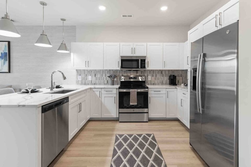 Sleek Modern Kitchen-Fully equipped kitchen with stainless steel appliances, white cabinetry, and a stylish backsplash. Features a spacious layout, island seating, and bright lighting for cooking and entertaining.