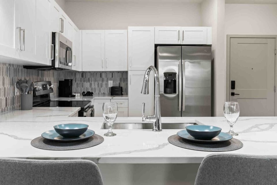 Modern Kitchen Dining-Bright kitchen with stainless steel appliances, marble island, and elegant backsplash. Features a breakfast bar set for two, blending style and functionality for a comfortable stay.