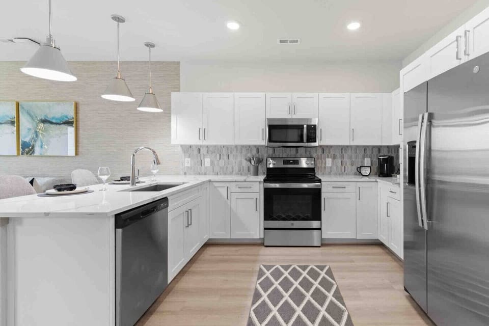 Modern Chef’s Kitchen-Spacious kitchen with sleek white cabinetry, stainless steel appliances, and a large refrigerator. Bright lighting and ample counter space make it perfect for cooking and entertaining.