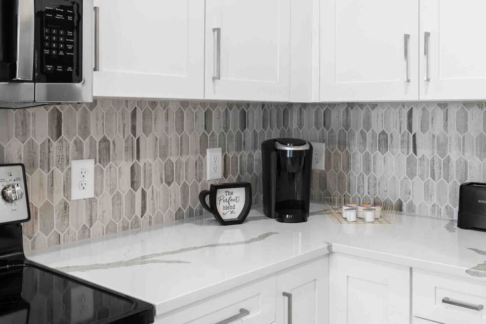 Modern Kitchen Essentials-Sleek kitchen setup with stainless steel appliances, stylish backsplash, and coffee maker with pods ready for guests. Perfect for convenient cooking and a fresh morning start.