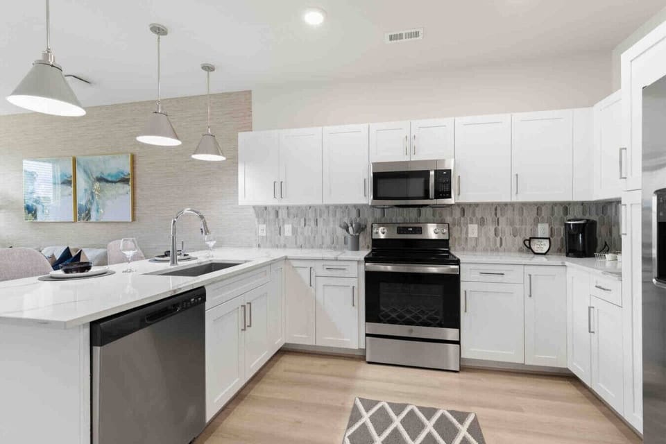 Modern Chef’s Kitchen-Spacious kitchen with sleek white cabinetry, stainless steel appliances, and a large refrigerator. Bright lighting and ample counter space make it perfect for cooking and entertaining.