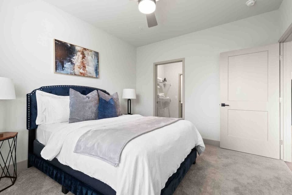 Elegant Bedroom Retreat – Unwind in this cozy space featuring a plush bed with soft linens, chic accent pillows, and modern lighting. Direct access to the walk-in closet ensures comfort and convenience throughout your stay.
