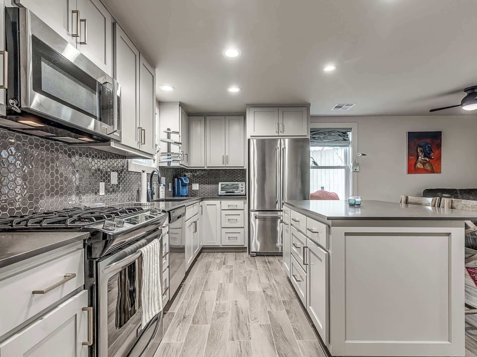 Cook like a pro in the fully-equipped guest house kitchen. This close-up view highlights the high-end stainless steel range, built-in microwave, and unique gray honeycomb tile backsplash.