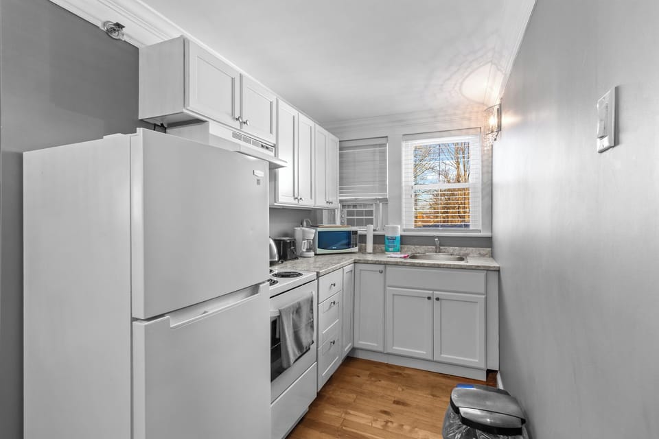 Fully equipped, modern white kitchen with all appliances, perfect for preparing meals.