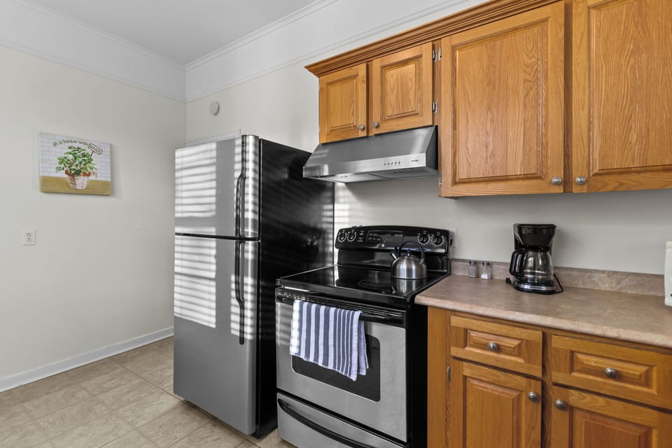 Prepare meals easily with stainless steel appliances, including a full-sized refrigerator and electric range with an overhead vent.