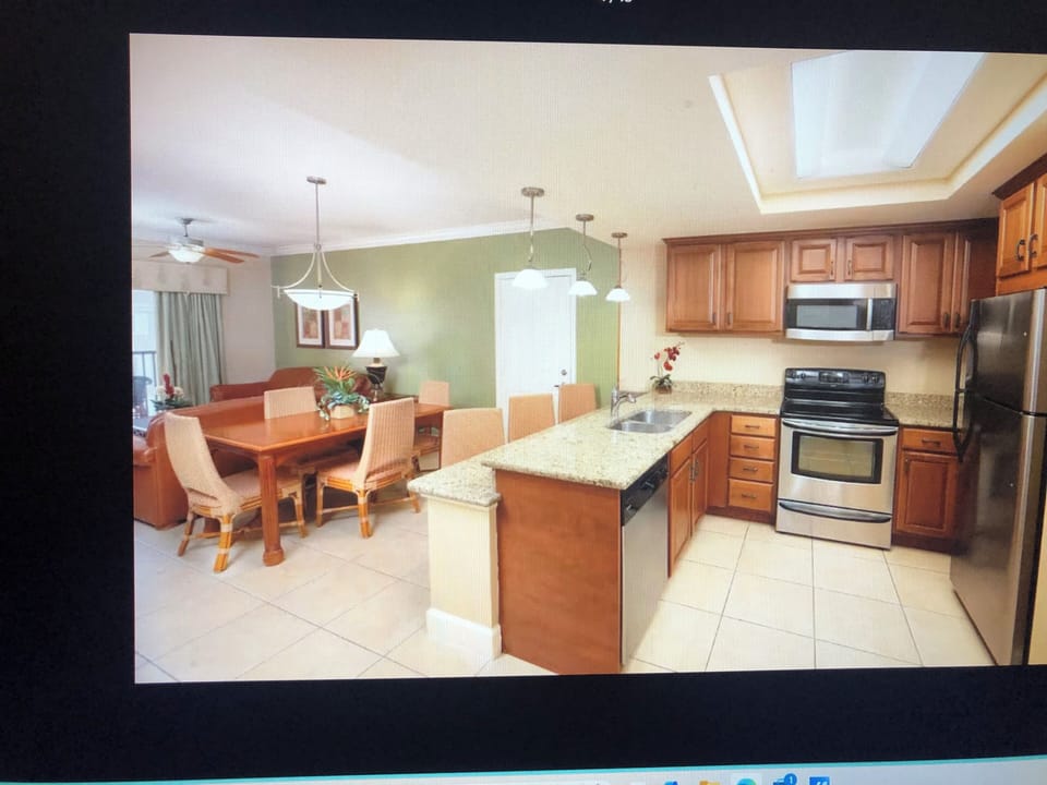 Partial view of living room, full kitchen and dining table.