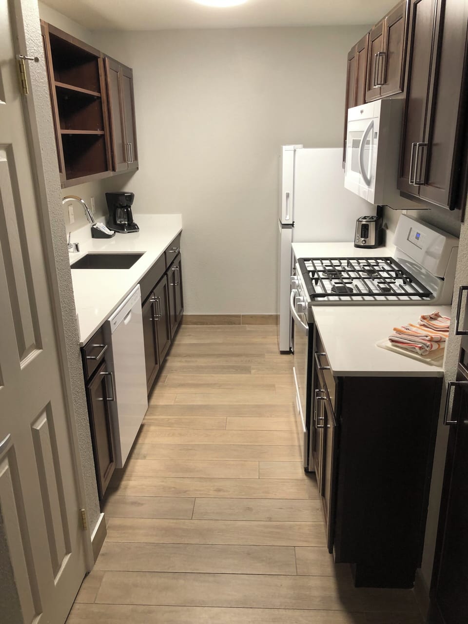 Kitchen stove, sink, fridge, toaster, coffee pot. utensils and plates in cabinet
