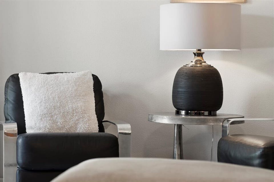 Stylish side table with modern lamp and cozy seating details adding charm to the bedroom