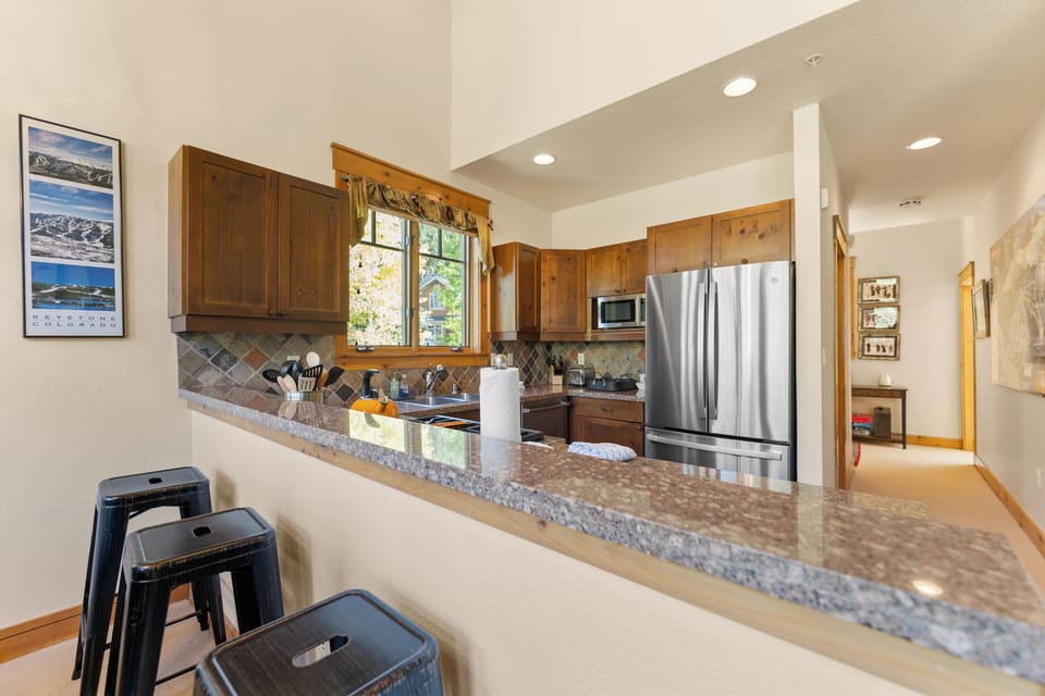 The full kitchen features granite countertops, stainless steel appliances, and breakfast bar for casual dining.
