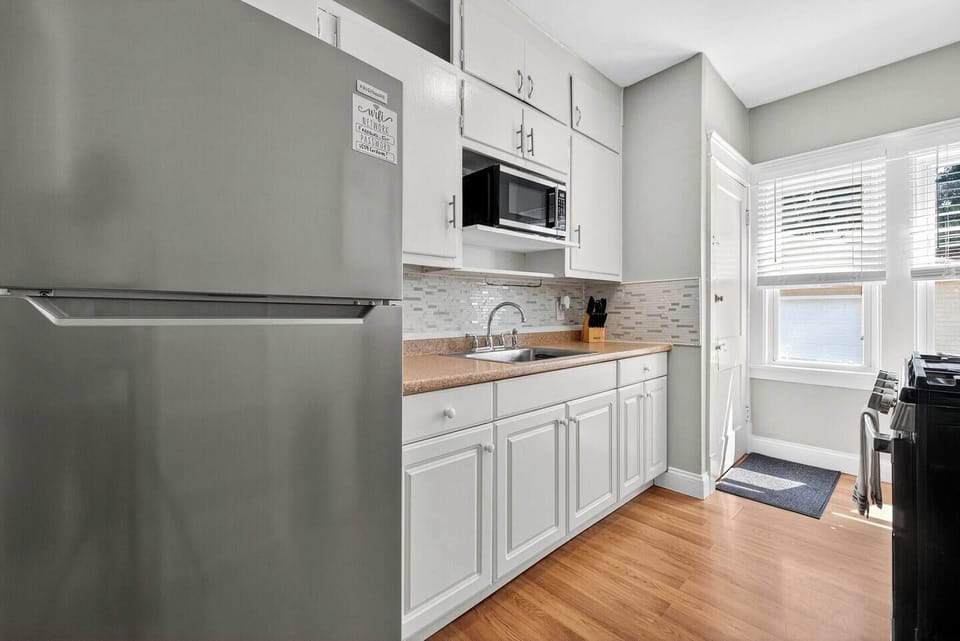 Functional kitchen setup with stove, full sink, microwave, and cooking utensils
