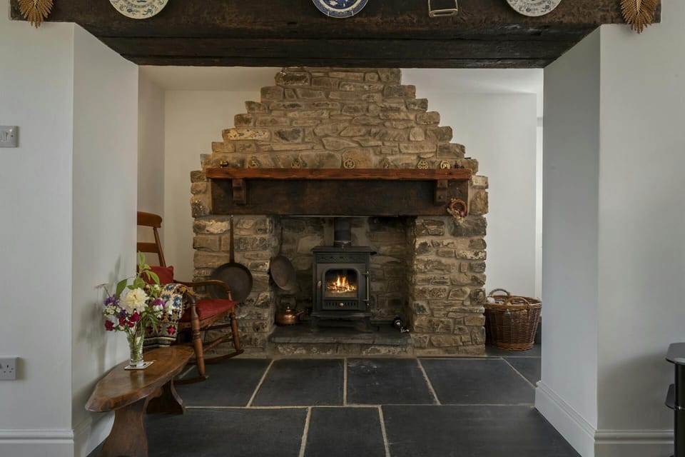 Wood burner fire with stone surround and wooden mantle piece. Slate floors