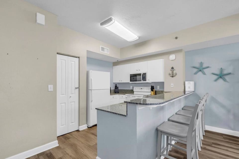 Fully equipped kitchen with granite countertops, bar seating, and all major appliances.