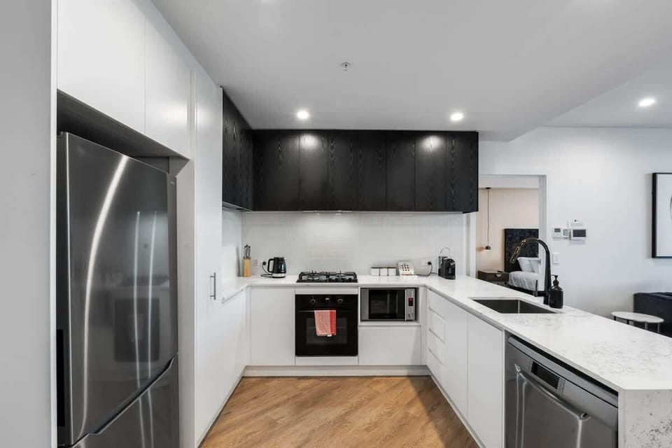 Fully equipped kitchen – Sleek black-and-white design with stone benchtops, gas cooktop, and stainless-steel appliances.