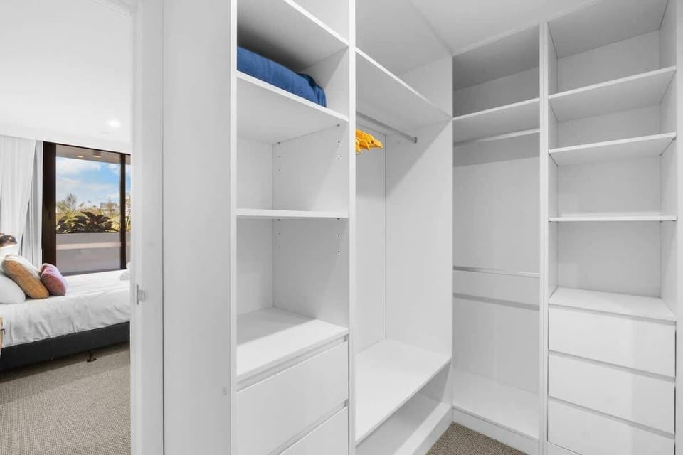 Walk-in robe – Generous storage with open shelving, drawers, and hanging space.