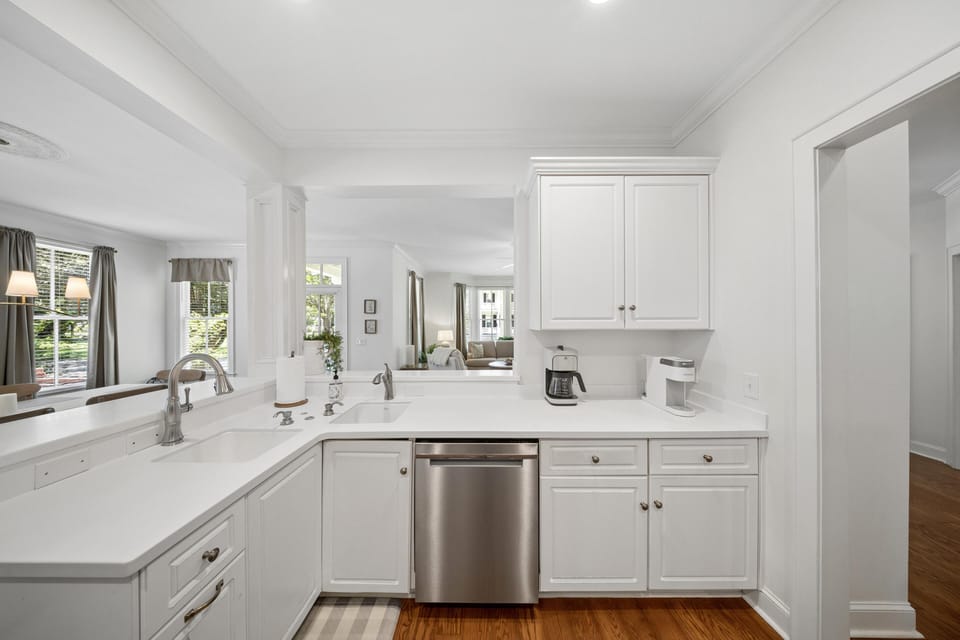 White quartz countertops surround a double sink with brushed nickel faucets in the bright kitchen.