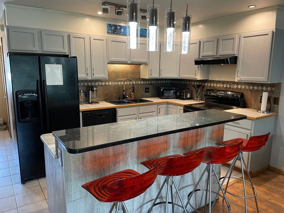 Chef's kitchen with microwave, coffee maker, toaster, utensils, plates, & pans. 