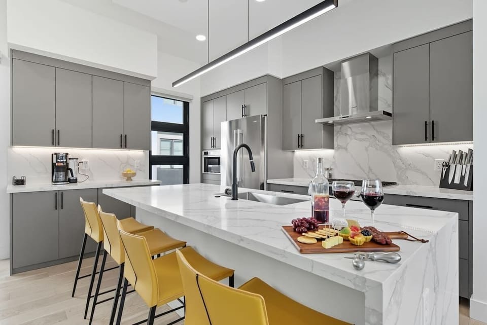 Fully equipped kitchen with stainless steel appliances, a sleek kitchen island with a breakfast bar for casual seating for 4, plus a large dining table for 8. (2nd Floor)