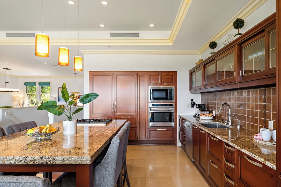 Enjoy cooking in this elegant space with granite countertops, rich wood cabinetry, and stainless steel appliances. The central island and cozy lighting make it perfect for relaxed meals and gatherings.