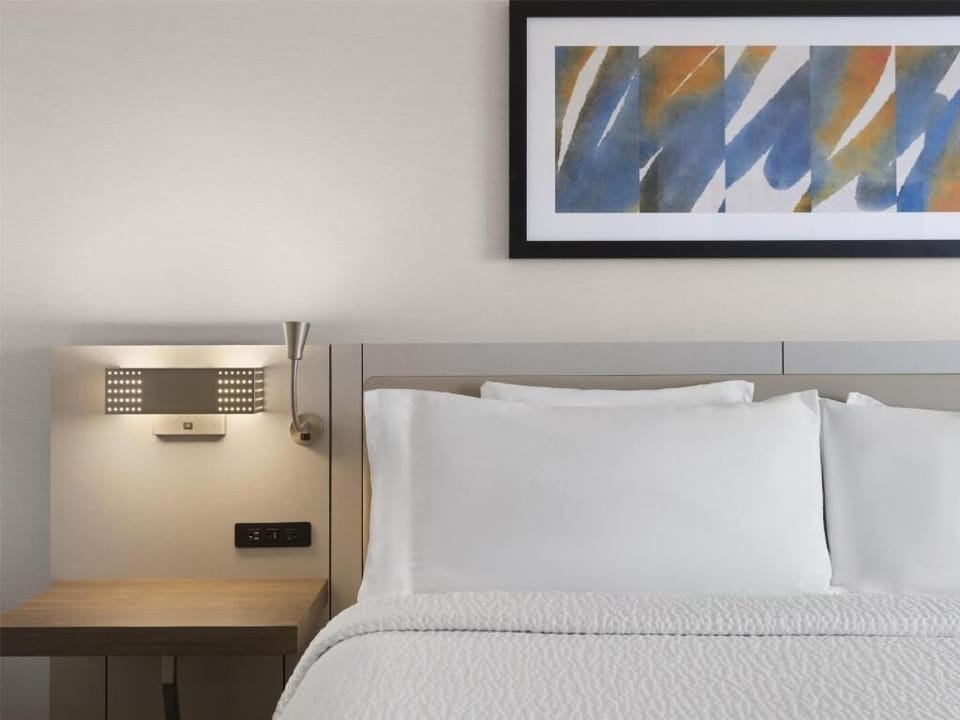 Sink into crisp pillows under warm, calming bedside lighting.