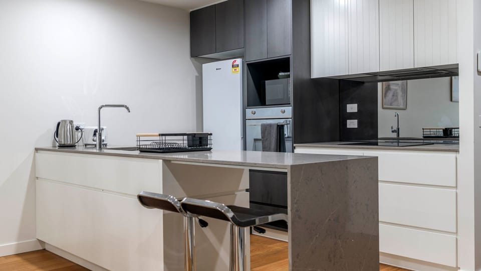 Sleek kitchen with stone benchtops and stainless steel appliances
