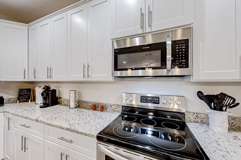 Fully equipped with premium stainless steel appliances, crisp white cabinetry, granite countertops, and a breakfast bar perfect for morning coffee.
