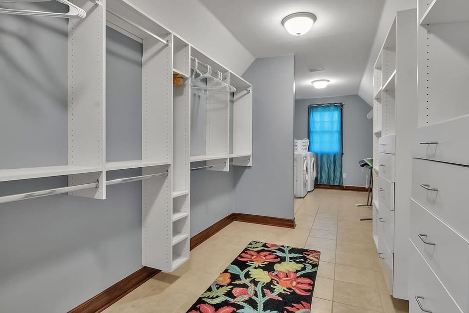 Step into a custom walk-in closet with private laundry and built-in storage