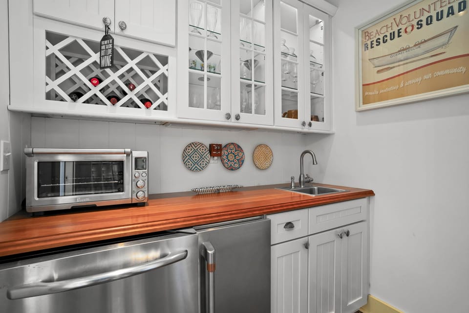 Butler’s pantry with wine rack, prep sink, and sleek stainless mini-fridge.