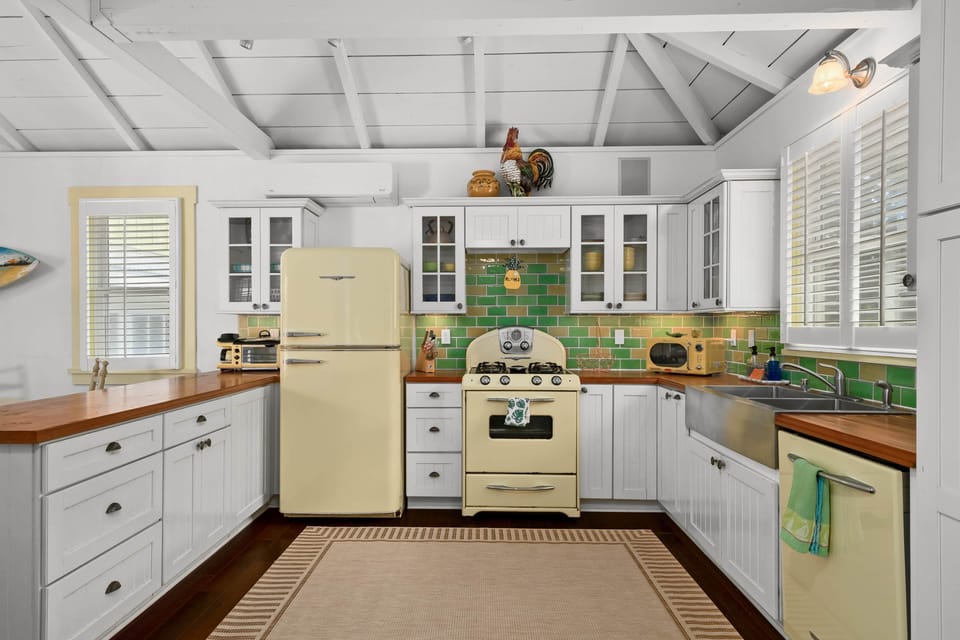 Charming 1940s-style kitchen—retro fridge & range, sunny windows, and green tile pop.
