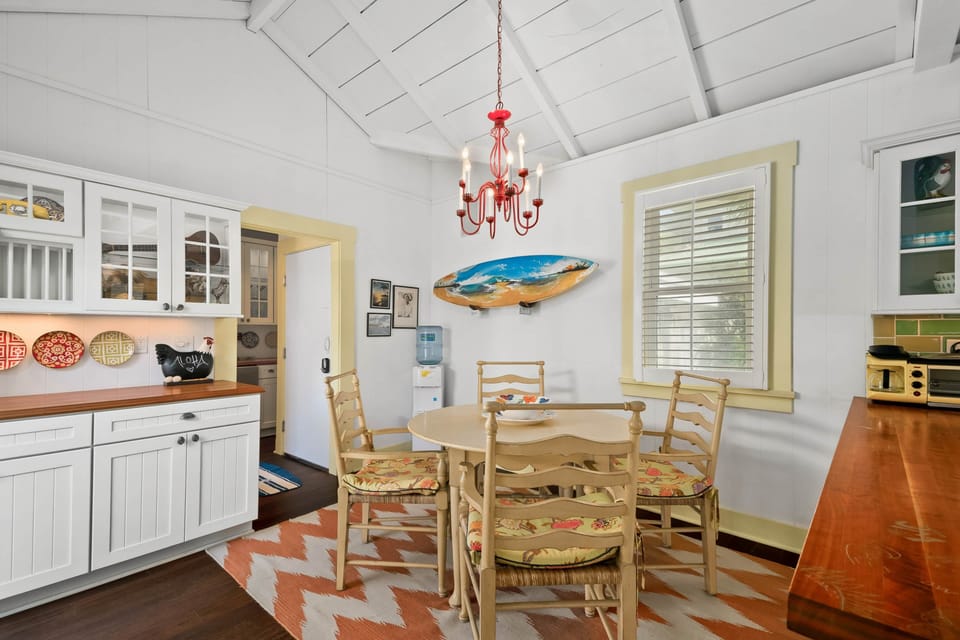 Cheerful dining nook—surf art, red chandelier, and vintage built-ins.