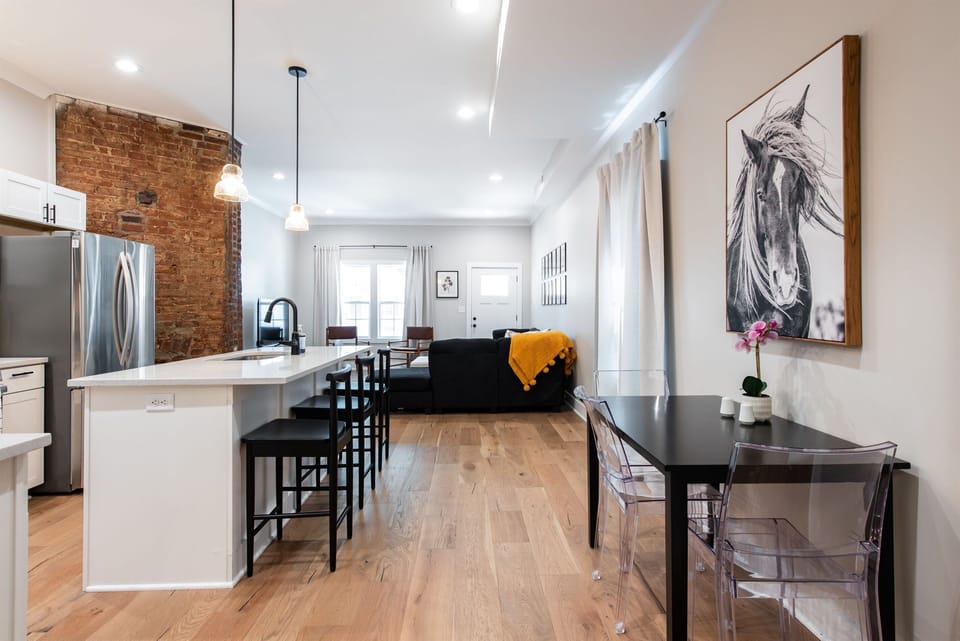 Dine in modern elegance at the sleek black table surrounded by clear acrylic ghost chairs. The stunning black and white horse canvas brings a touch of local equestrian flair to your meals.