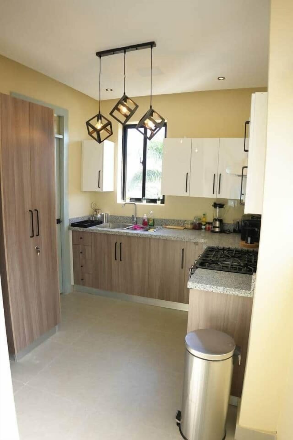 Modern and functional kitchen with sleek wood cabinets, granite countertops, stylish lighting, and all the essentials—perfect for cooking up your favorite meals in comfort.