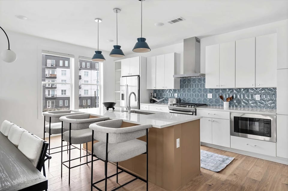 Cook together without the crush. The island seats three, white cabinets line the walls, and that blue hexagon backsplash keeps the vibe fresh while you're prepping dinner as a group in Nashville