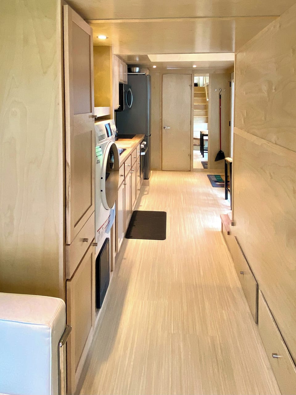 A warm wood walkway from living area through the open kitchen to the bathroom.